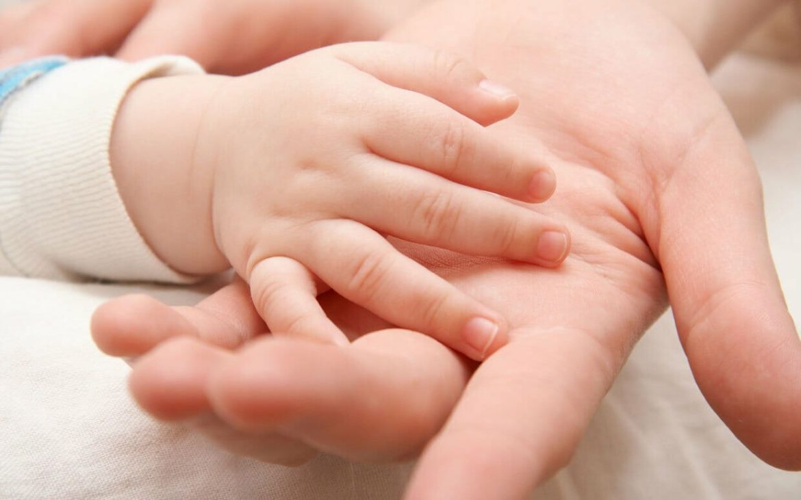 A small baby holding the hand of his baby